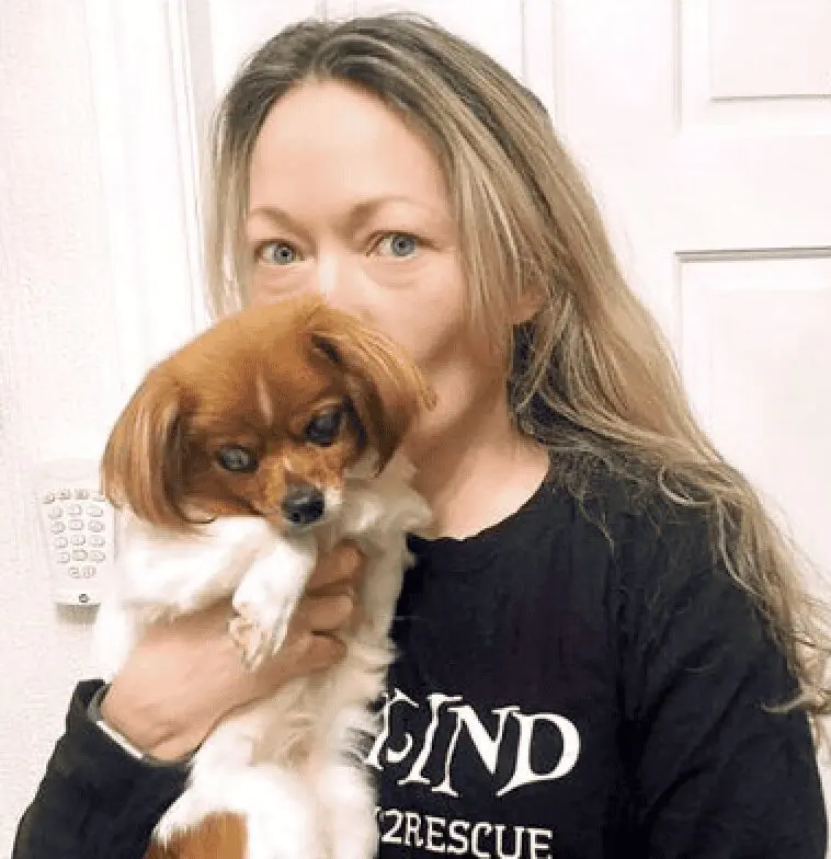 A photo of Paws2Rescue team member Rachel kissing a very small dog on the back of the head